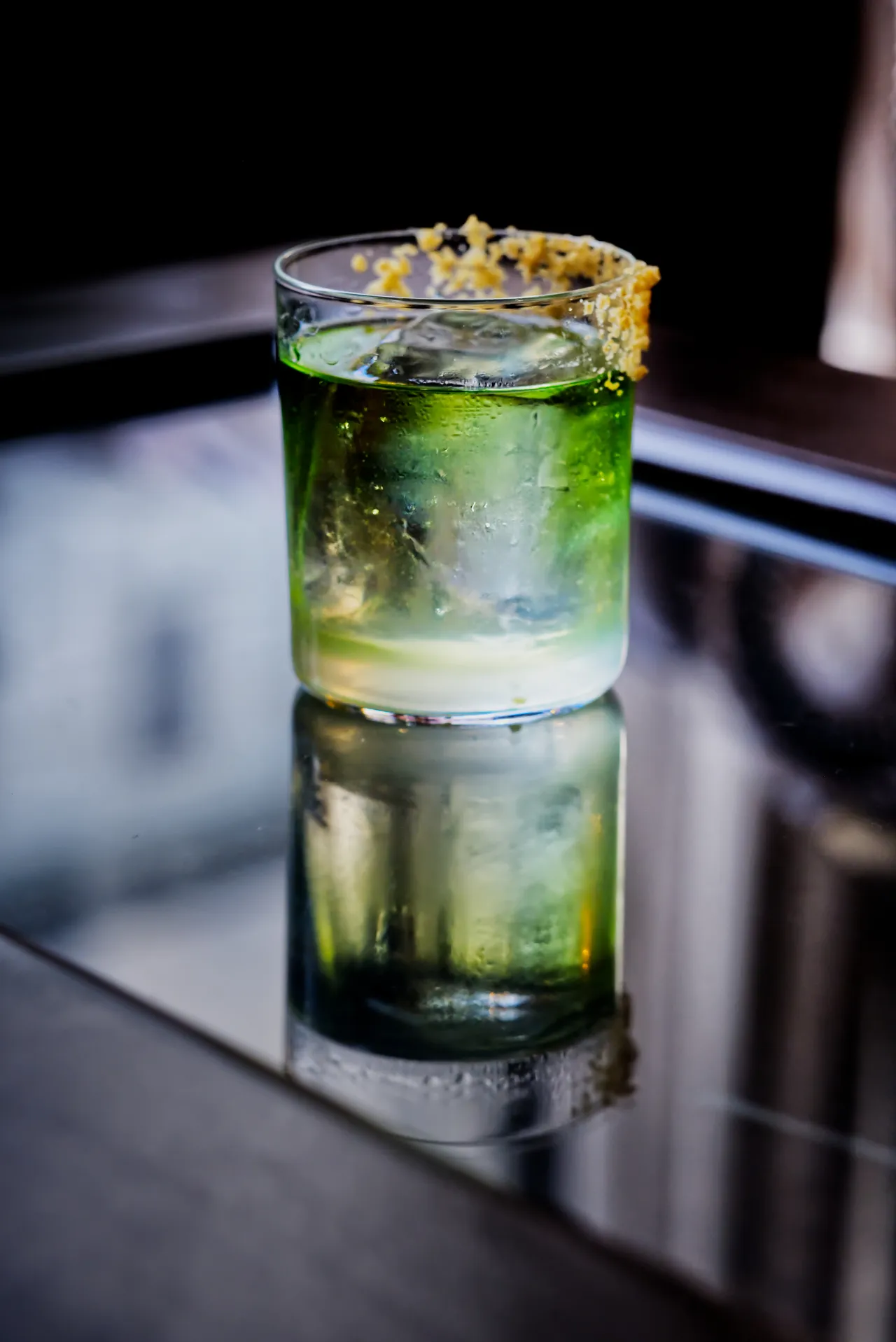 Green cocktail with a citrus rim reflected on a mirrored counter
