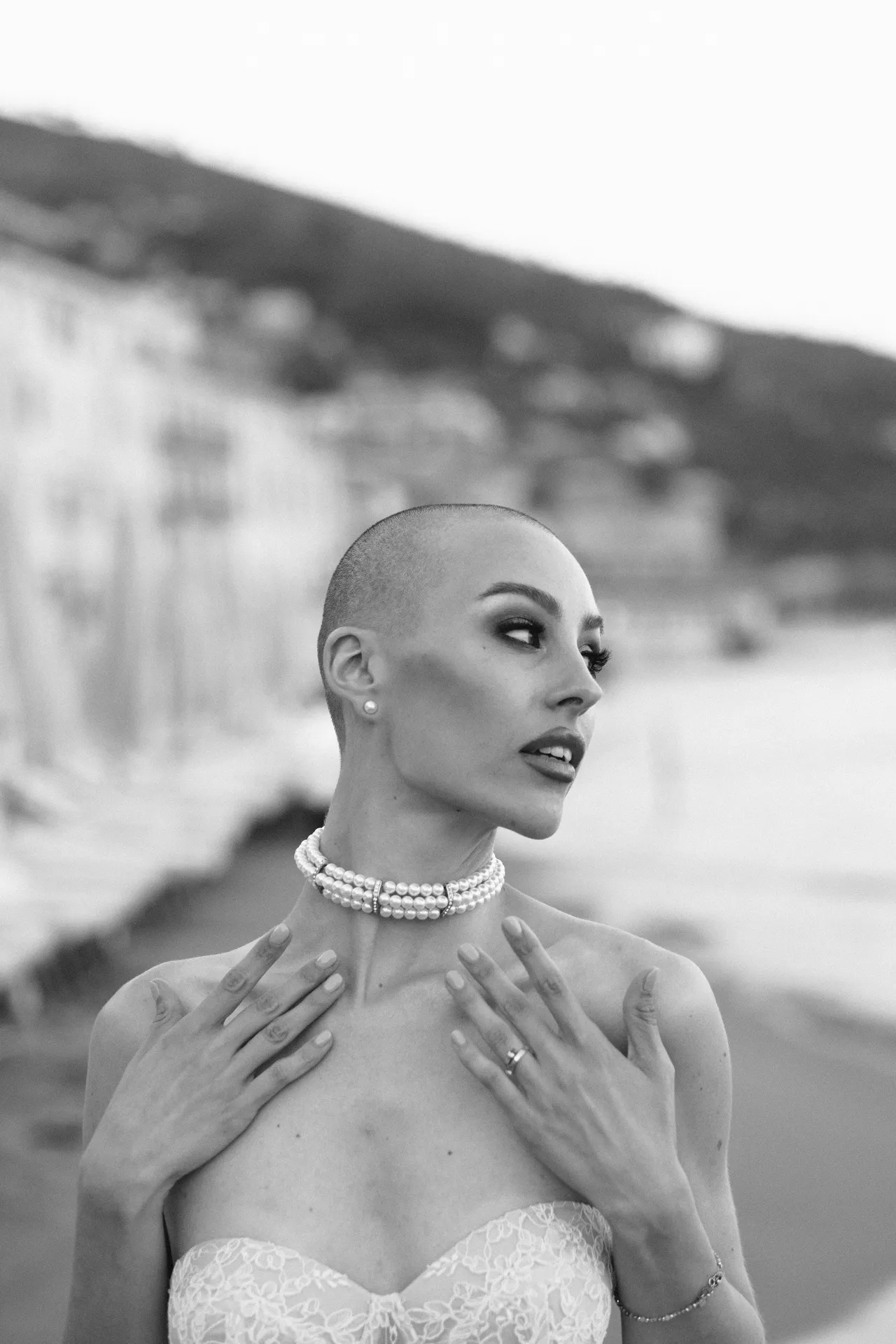 Woman with a pearl choker, hands resting on her chest, in black and white