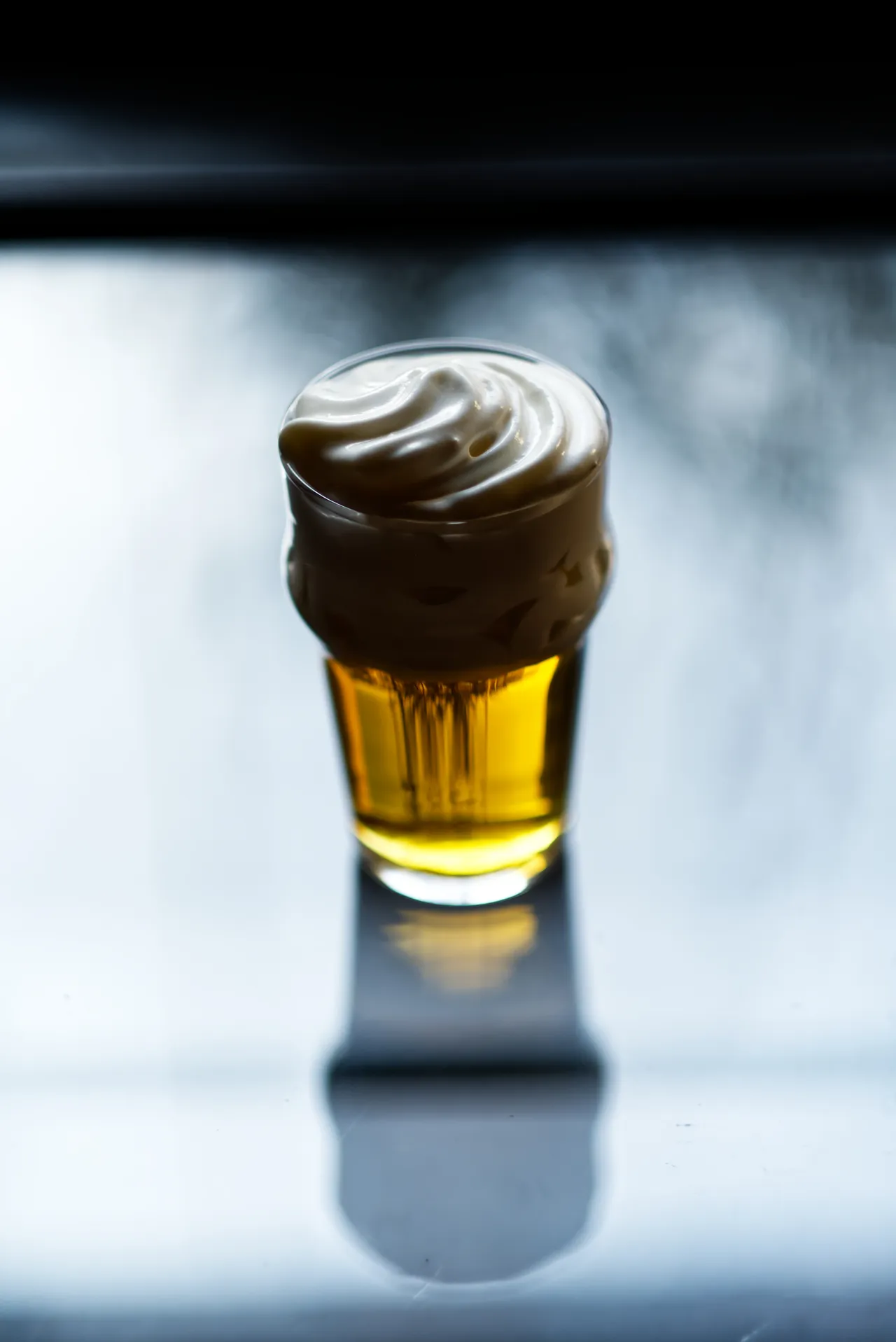 Golden drink crowned with foam, backlit