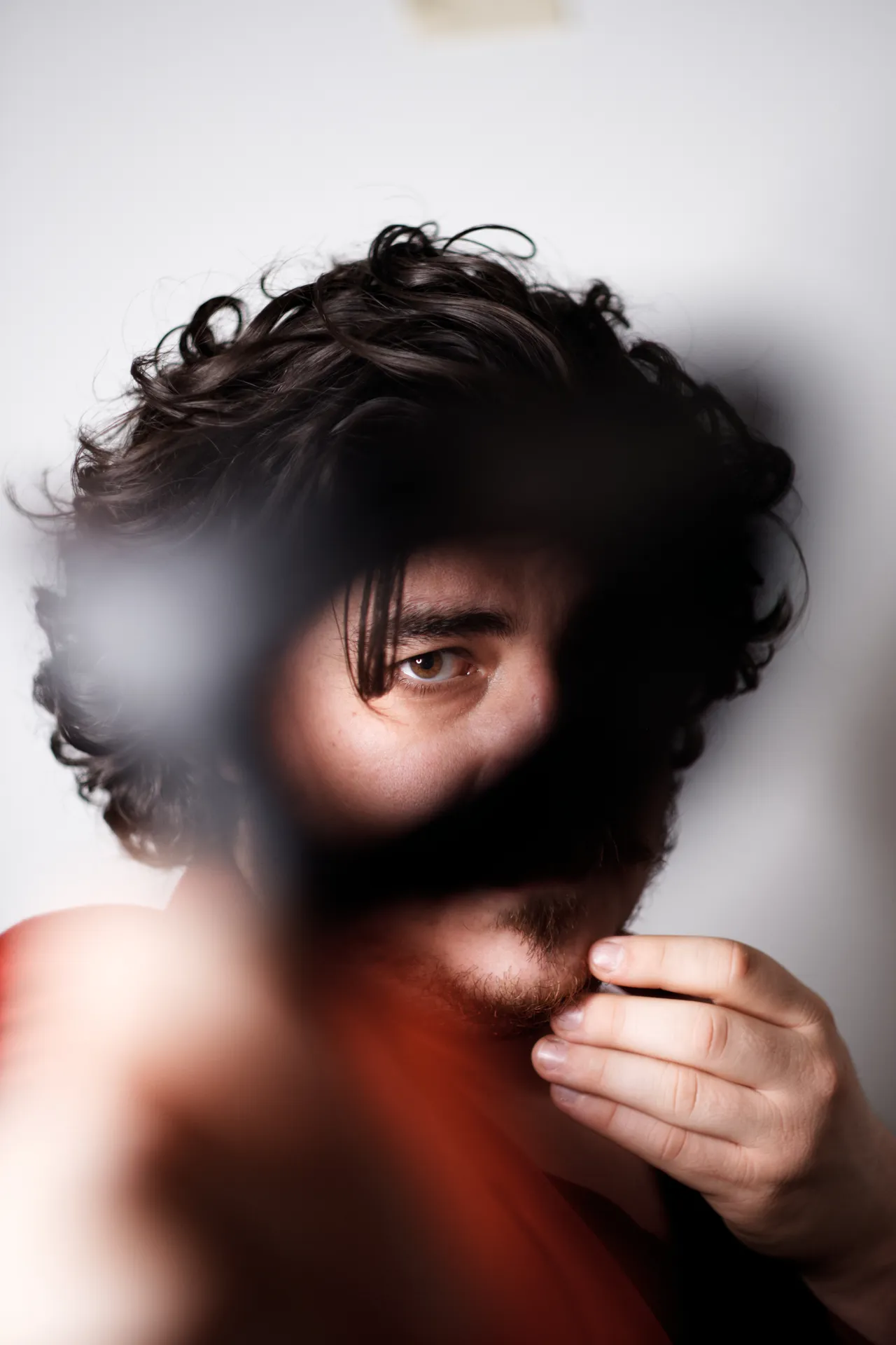 Face of a curly-haired man looking past a blurred object in the foreground