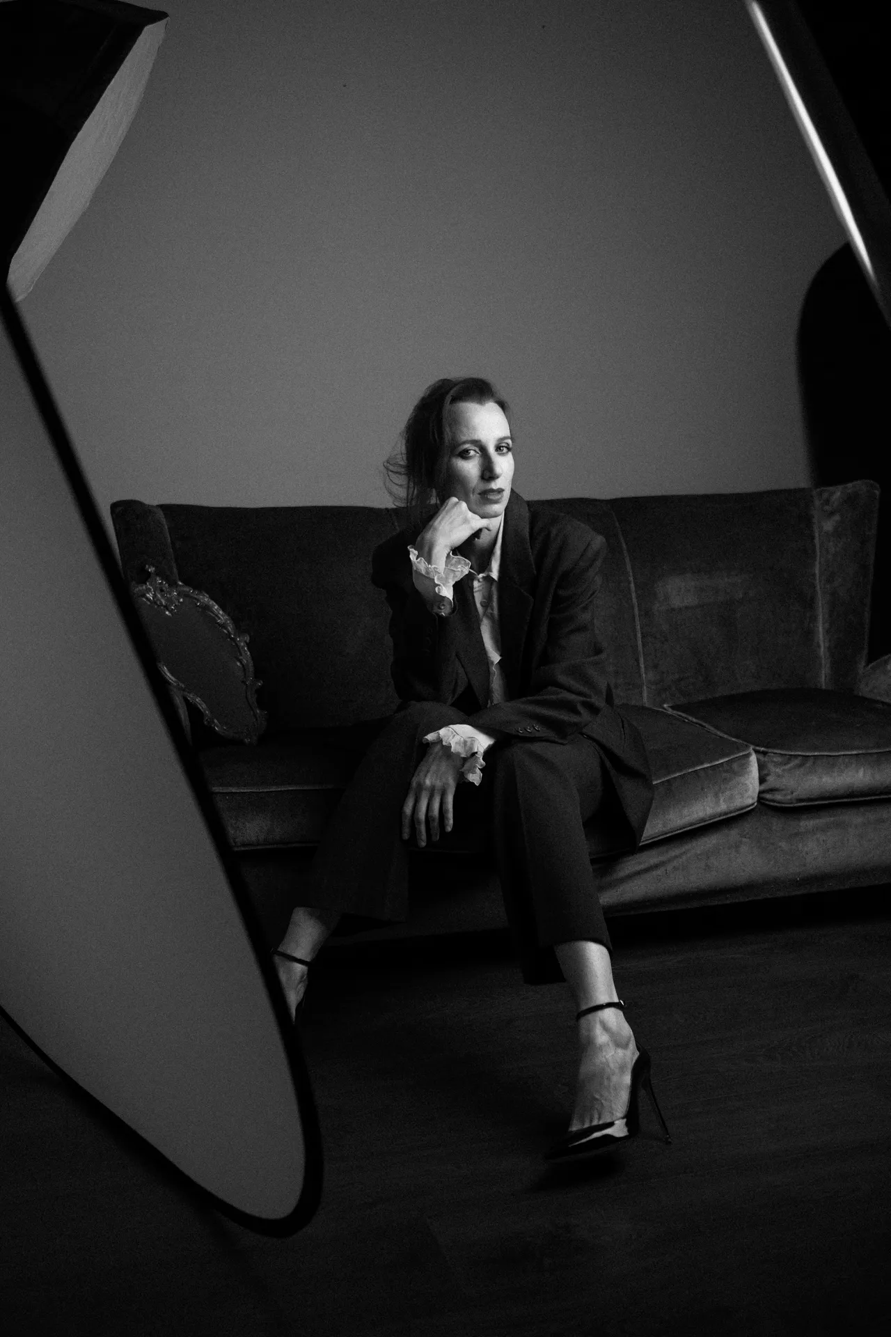 Wide black and white view of the woman on the sofa, a large reflector panel in the foreground