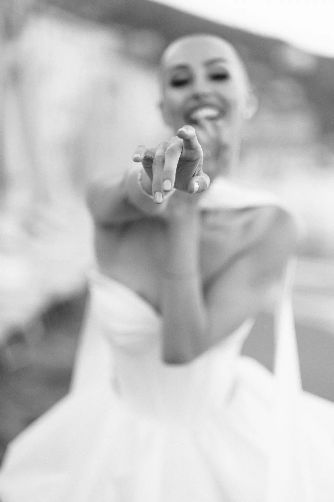 Smiling woman reaching towards the lens, her hand blurred in the foreground