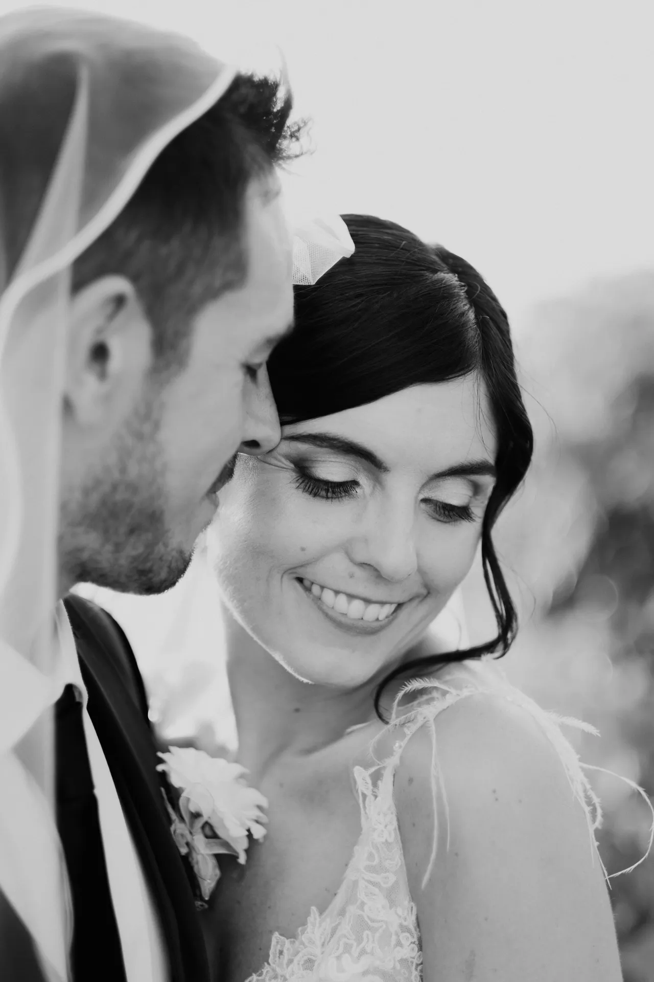 The bride smiles, looking down, as the groom watches her closely