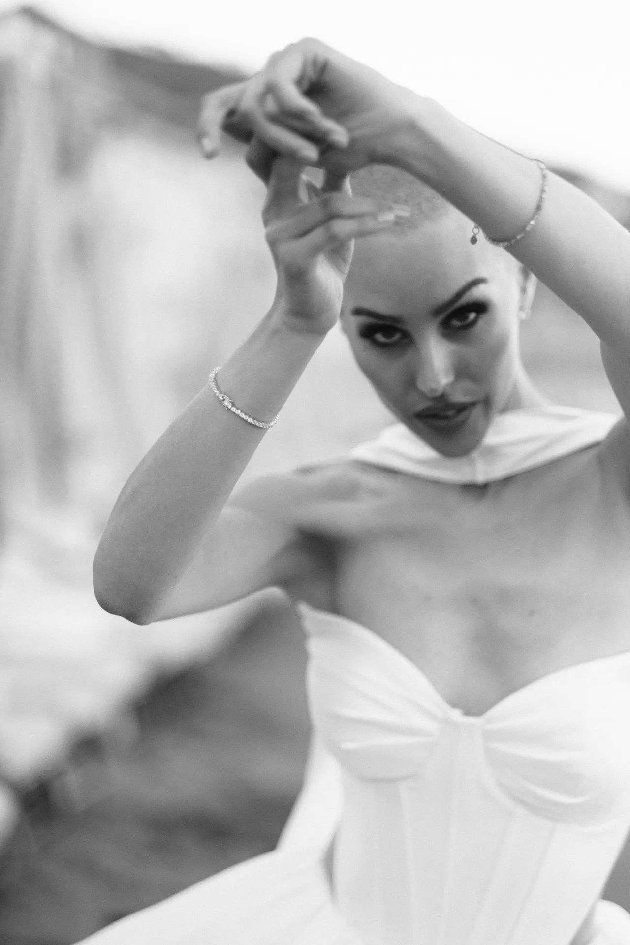 Woman lifting a hand above her head, looking down towards the lens