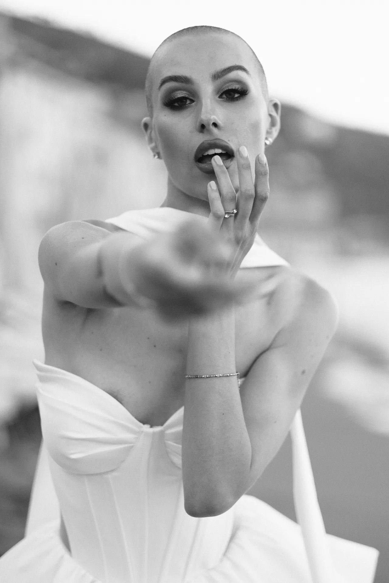 Woman with her fingers at her lips and her other hand stretched towards the camera