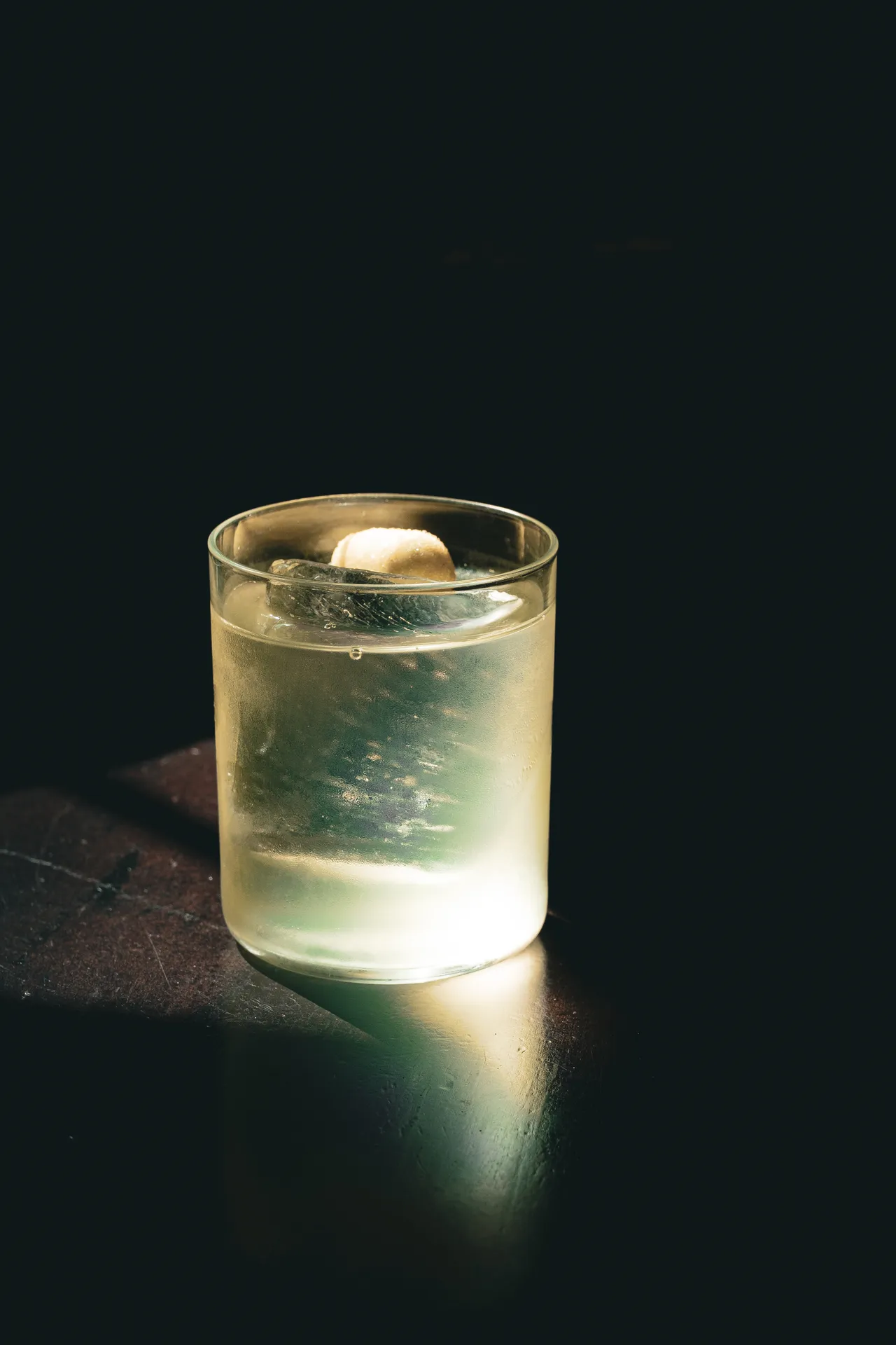 Frosted tumbler with a clear drink emerging from darkness