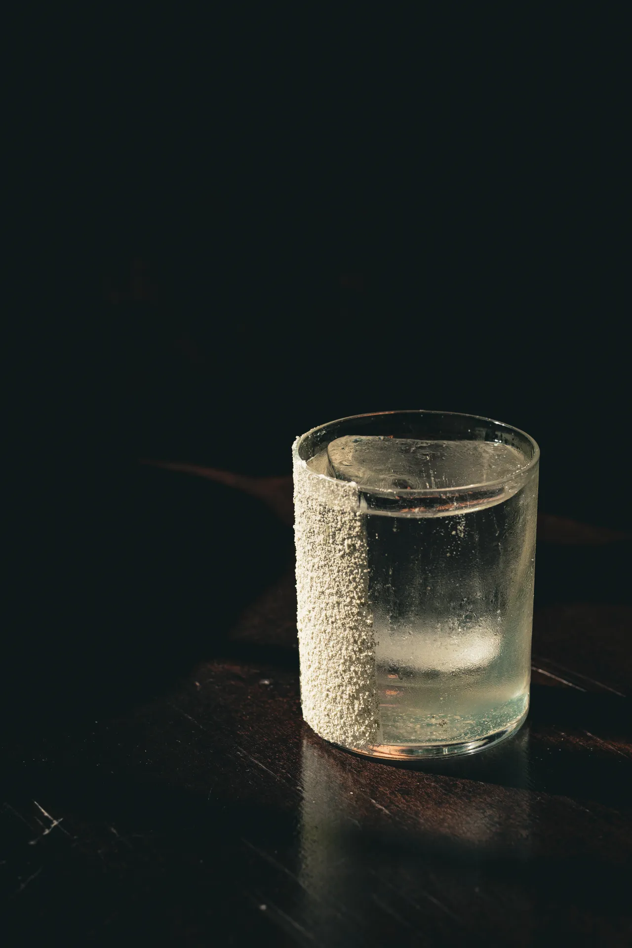 Glass with a frosted rim on a dark surface, side light