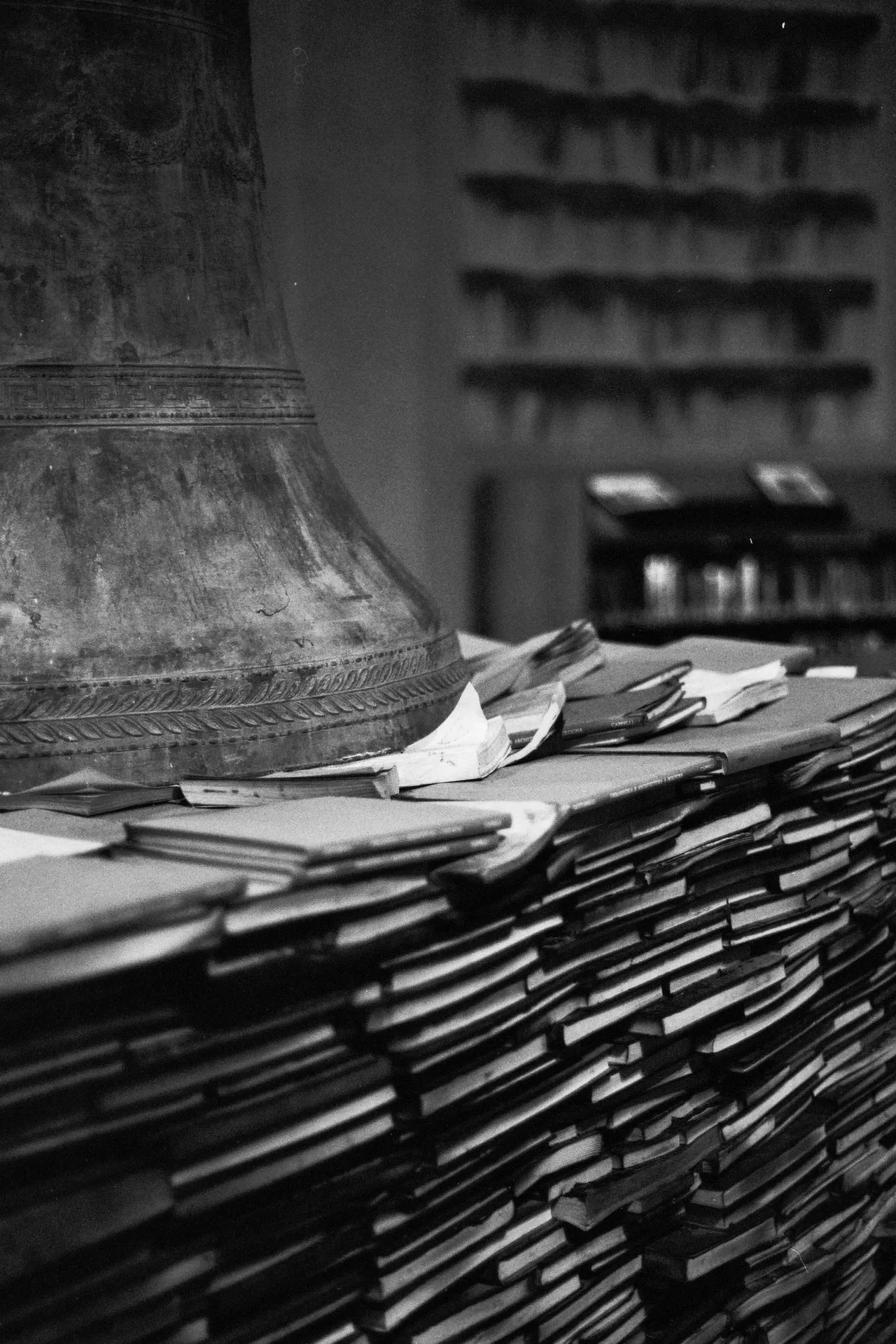 Pile di vecchi libri sotto una grande campana di bronzo, in bianco e nero
